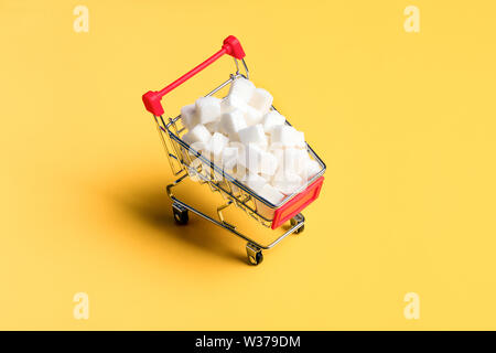 Sugar cubes concept. White sugar cubes in the shopping cart on the orange background Stock Photo