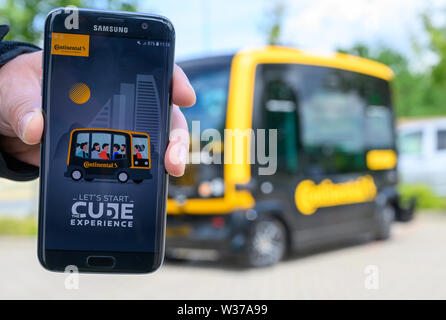 03 July 2019, Lower Saxony, Hanover: A man is holding a smartphone on which the 'Cube Experience' app from the technology company Continental is opened, which can be used to call the driverless, electrically powered Cube minibus (Continental Urban Mobility Experience). Photo: Christophe Gateau/dpa Stock Photo