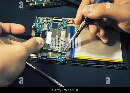 Tablet repair. Soldering the battery contacts Stock Photo