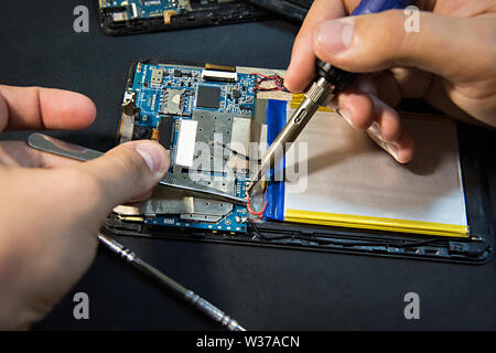 Tablet repair. Soldering the battery contacts Stock Photo