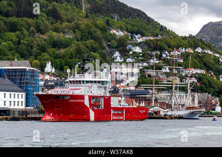 Offshore multi service standby rescue vessel Ocean Response in the port of Bergen, Norway. Tall ship, barque Statsraad Lehmkuhl in background. Stock Photo