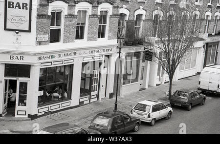 1970s, historical, view from above, from a window of cars parked in in a street and the Brasserie Du Marche, a french style cafe restaurant on the famous Portobello Rd, Notting Hill, West London, W10, England, UK. Stock Photo