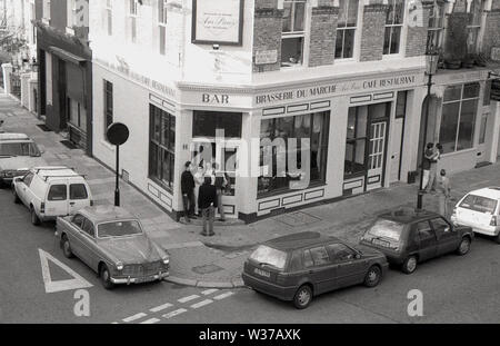 1970s, historical, view from above, from a window of cars parked in in a street and people at the entrance of the Brasserie Du Marche, a french style cafe restaurant on the corner of the famous Portobello Rd, in Notting Hill, West London, W10, England, UK. Stock Photo