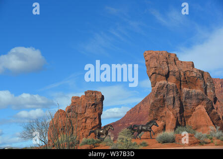 A beautiful view of a naturally eroded red mountain with trotting horses sculpted in bronze.  Photographed near Ivins, Utah, USA. Stock Photo