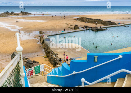 Bude Beach, North Cornwall, England. Saturday 13th July 2019. UK Weather. Lower temperatures, overcast skies and a cooling breeze on the North Cornish coast as Bude still welcomes holidaymakers to the popular coastal resort in North Cornwall. Credit: Terry Mathews/Alamy Live News Stock Photo