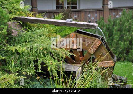 Landscape and arrangement. Driving mill wheel with falling water in the garden. Stock Photo