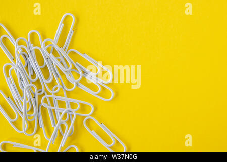 White paperclips on a bright yellow background Stock Photo