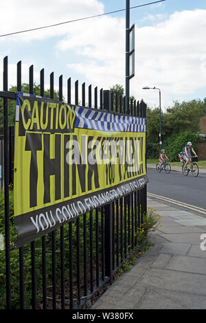 adult and children cycle passed a think before you park, sign aimed at drivers outside a school in twickenham, middlesex, england Stock Photo