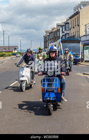 Scooter Rally Ride Out in Lancashire, UK July 2019. Morecambe Rides Again; The First Kick Scooter Collective and the Vespa Club of Morecambe (COG159) host a rally circuit in the resort which has the honour of being a Vespa Club Of Britain signing on event. Morecambe is back on the scootering map with the first proper scooter rally since the 1980s being held. Scooterists roared into town on their Vespas & Lambrettas congregating at Happy Mount Park before a mass rally along the seafront promenade. Stock Photo