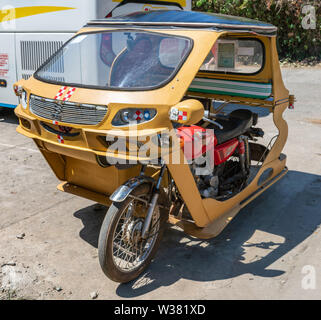 Puerto Princesa, Palawan, Philippines - March 3, 2019: Street view. Yellow taxi motor-tricycle parked in street. Stock Photo