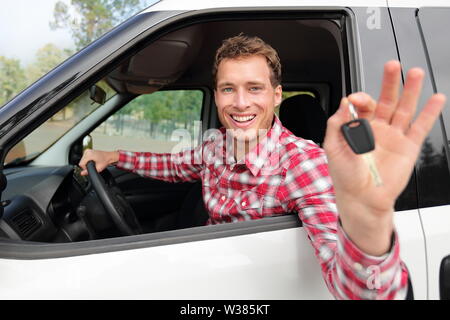 New cars concept - man driving car showing car keys happy looking at camera. Caucasian male driver on road trip using car rental. Stock Photo