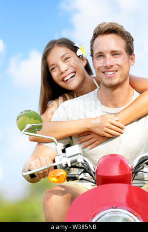 Scooter driving Happy young couple in love. Multiracial couple having fun in the free outdoor. Smiling Caucasian man and Asian woman. Stock Photo