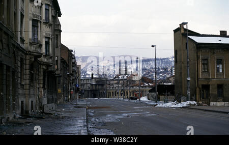2nd April 1993 During the Siege of Sarajevo: a landscape of burnt-out and wrecked buildings along Hiseta Street, which is in the sights of the sniper. The shell of a burnt-out car lies on its roof on the pavement. Stock Photo