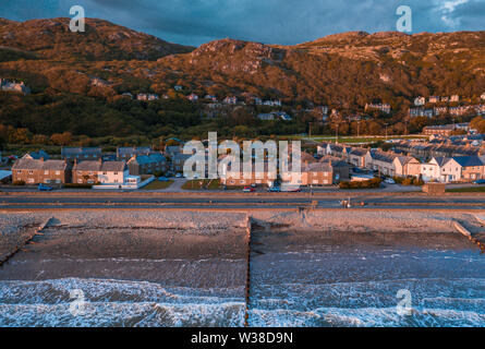 Sea waves breaking on the shore of scenic coastal town at stormy sunset. Barmouth in North Wales, UK Stock Photo