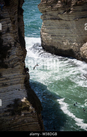 Cliff jumpers compete in Round 1 of 3 at Rouche Rocks in Beirut. Part of a RedBull sponsored world tour, high divers from all over the globe are taking part in a cliff diving competition from scenic locations across the planet. Jumping from heights in excess of up to 27m they encountered strong winds and rough seas today, continuing with the competition despite having to be zip-lined over to the dive platform due to strong waves preventing boat access. Stock Photo