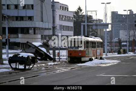 2nd April 1993 During the Siege of Sarajevo: a wrecked tram next to the Assembly Building on Sniper Alley. A burnt-out car lies on its roof in front of the tram and next to them is the wreckage of a booth. Stock Photo
