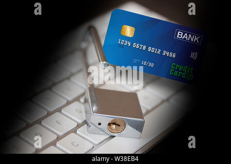 Stainless padlock and a credit card in front of a computer keyboard surrounded with a black shadow. Credit card data security and network security con Stock Photo