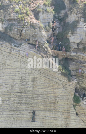 Divers prepare to jump into the waters of the Mediterranean from the height of the Pigeon Rocks during the Red Bull World Cliff Diving Championships which is held for over two days. Stock Photo