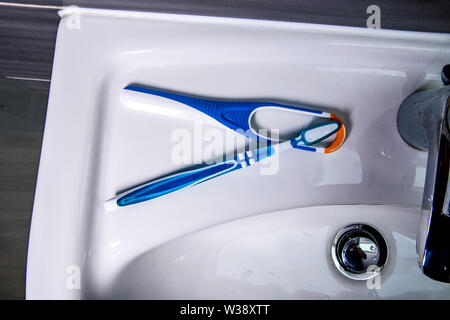 Tongue cleaner with toothbrush on the wash basin in the bathroom Stock Photo