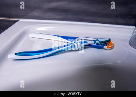 Tongue cleaner with toothbrush on the wash basin in the bathroom Stock Photo
