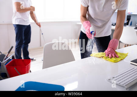 Two Janitor Cleaning The Desk And Mopping Floor In The Office Stock Photo