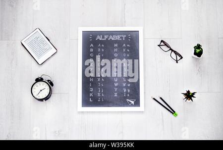 Overhead shot of a small whiteboard with alphabet letters on it on a white wooden background Stock Photo