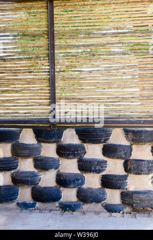 Wall made from old tyres and wooden branches at a school for building in Africa.  This reuse cuts down on waste and provides cheap building materials.  Namibia Stock Photo