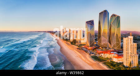 Rising sun shining on modern urban towers of Surfers paradise in Australian Gold Coast facing endless waves of Pacific ocean - aerial panoramic view. Stock Photo