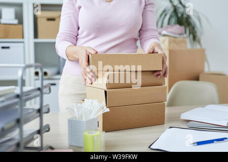 Stack of packed boxes with orders of online shop clients and manager taking one of them Stock Photo