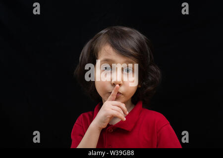 Cute  kid put index finger over lips for  quiet gesture Stock Photo