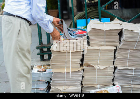 Person taking a Evening Standard Newspaper from a stand at the entrance of the tube station Stock Photo