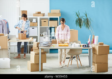 Young woman in casualwear preparing pullover for packing before sending online order to client Stock Photo