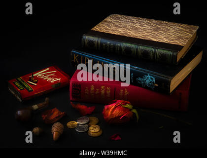 Vintage still life with stacked up books and pipe smoking apparatus on black background hardbound, stacked, vintage, classic books closed on a desk wi Stock Photo