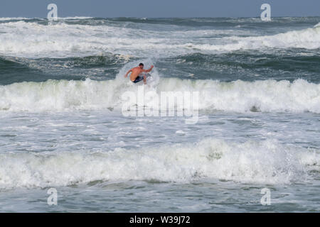 Panama City, Florida, USA. Surfer at St. Andrews State Park as Hurricane Barry churns in the Gulf of Mexico Stock Photo