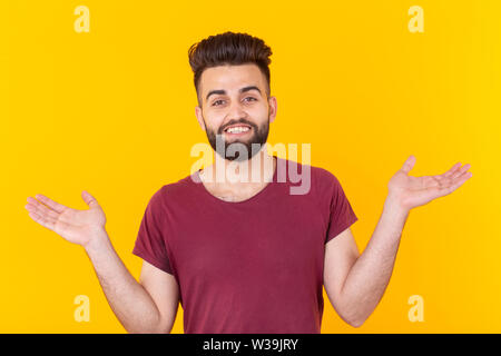 Portrait of a young Indian surprised man with dew in a shirt dosing against a yellow background. Concept of news and advertising. Stock Photo