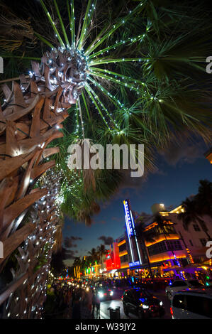 MIAMI - DECEMBER 30, 2018: Visitors stroll along the lights of Ocean Drive, with Art Deco neon lights and holiday palm trees. Stock Photo