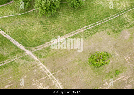 aerial view of rural landscape with country dirt road among green meadow
