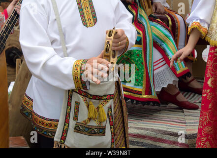 A man in national dress plays in the ensemble on an old folk musical instrument Stock Photo