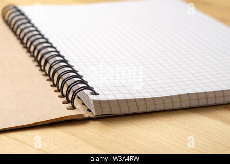 Notebook with checkered sheets on a wooden table. Side view Stock Photo