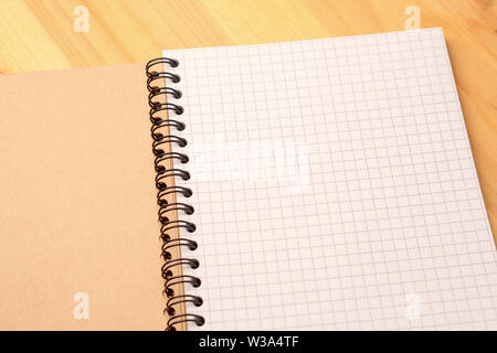 Notebook with checkered sheets on a wooden table. Top view Stock Photo
