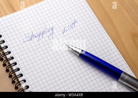 Blue pen on a notebook with sheets in a cage. Sign Shopping List Stock Photo