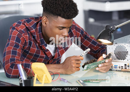 computer technician using magnifying glass Stock Photo