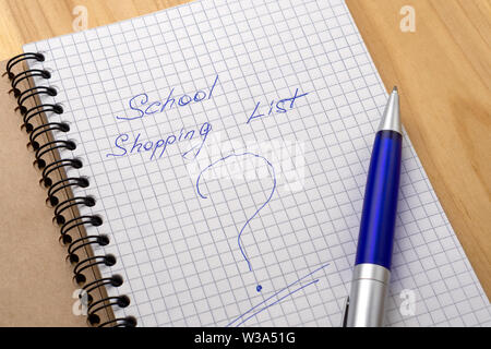 Blue pen on a notebook with sheets in a cage. Sign shopping list and question mark Stock Photo