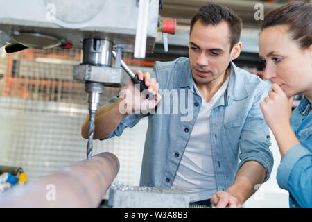 young technicians working on pillar drilling machine in workshop Stock Photo