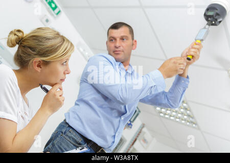 man testing a ceiling mounted detector Stock Photo