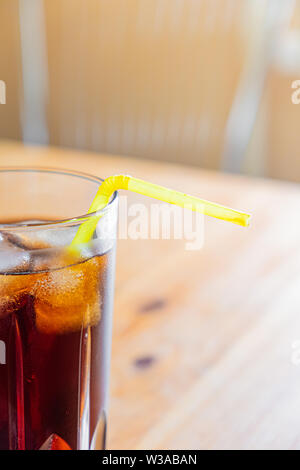Icy cold beverage in a glass, close-up view. Glass of cool fizzy drink with ice on a wood table, vertical shot Stock Photo