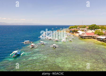 Coast of Cebu island, Moalboal, Philippines, top view. Boats near the shore in sunny weather. Seascape with coral reef near the shore. Stock Photo
