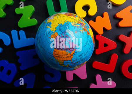 Earth globe model on colorful letters on a black background Stock Photo
