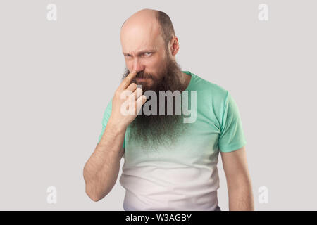 You are liar. Portrait of angry middle aged bald man with long beard in green t-shirt standing, looking and pointing at his nose, showing lie gesture. Stock Photo