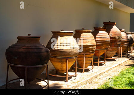 Huge earthenware jugs exhibited in the sun outside. Old pottery pots outside. Old orange clay jugs Stock Photo